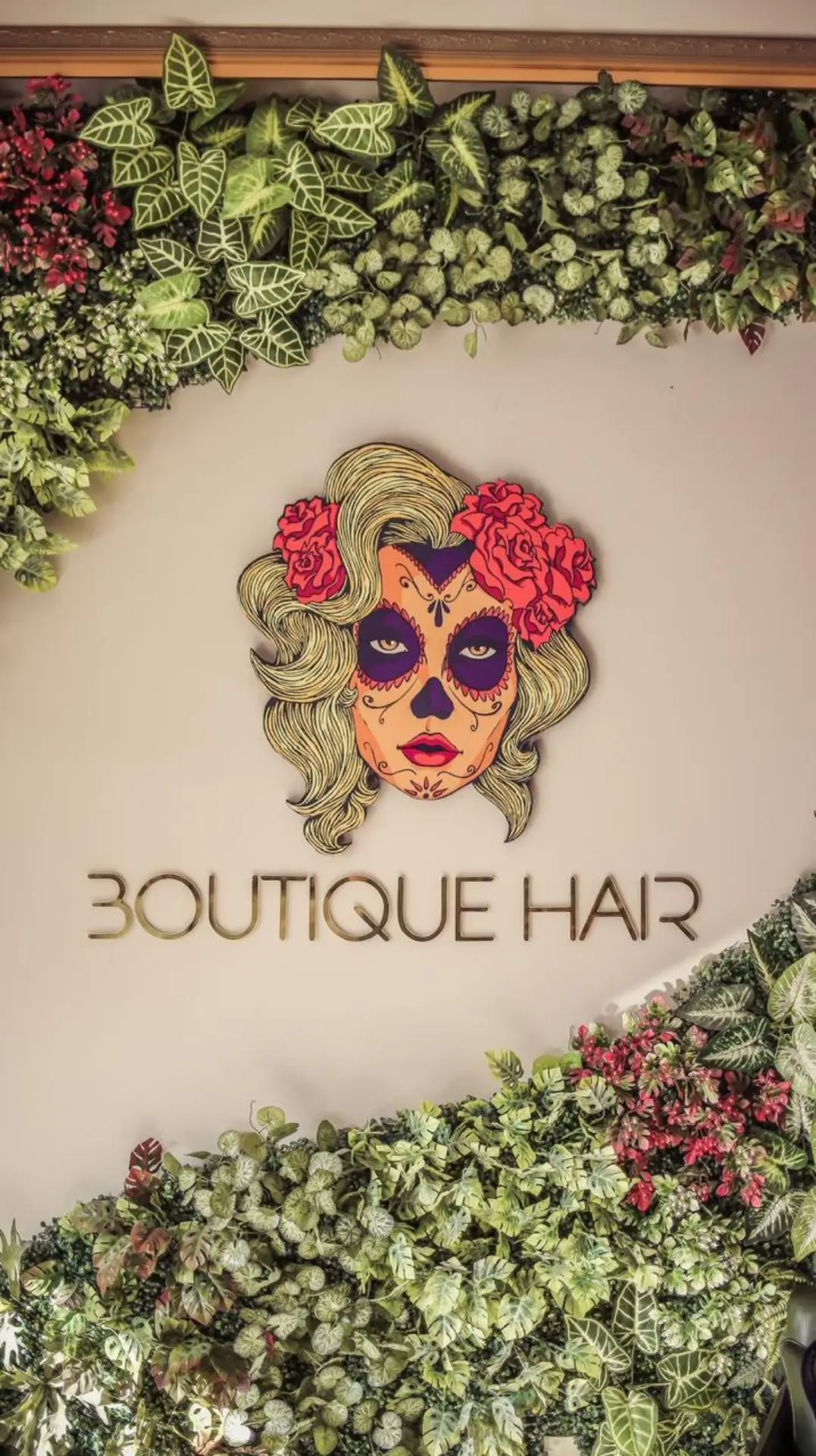 Parede com a logo do Ivam Marcos Boutique Hair cercada por jardim vertical